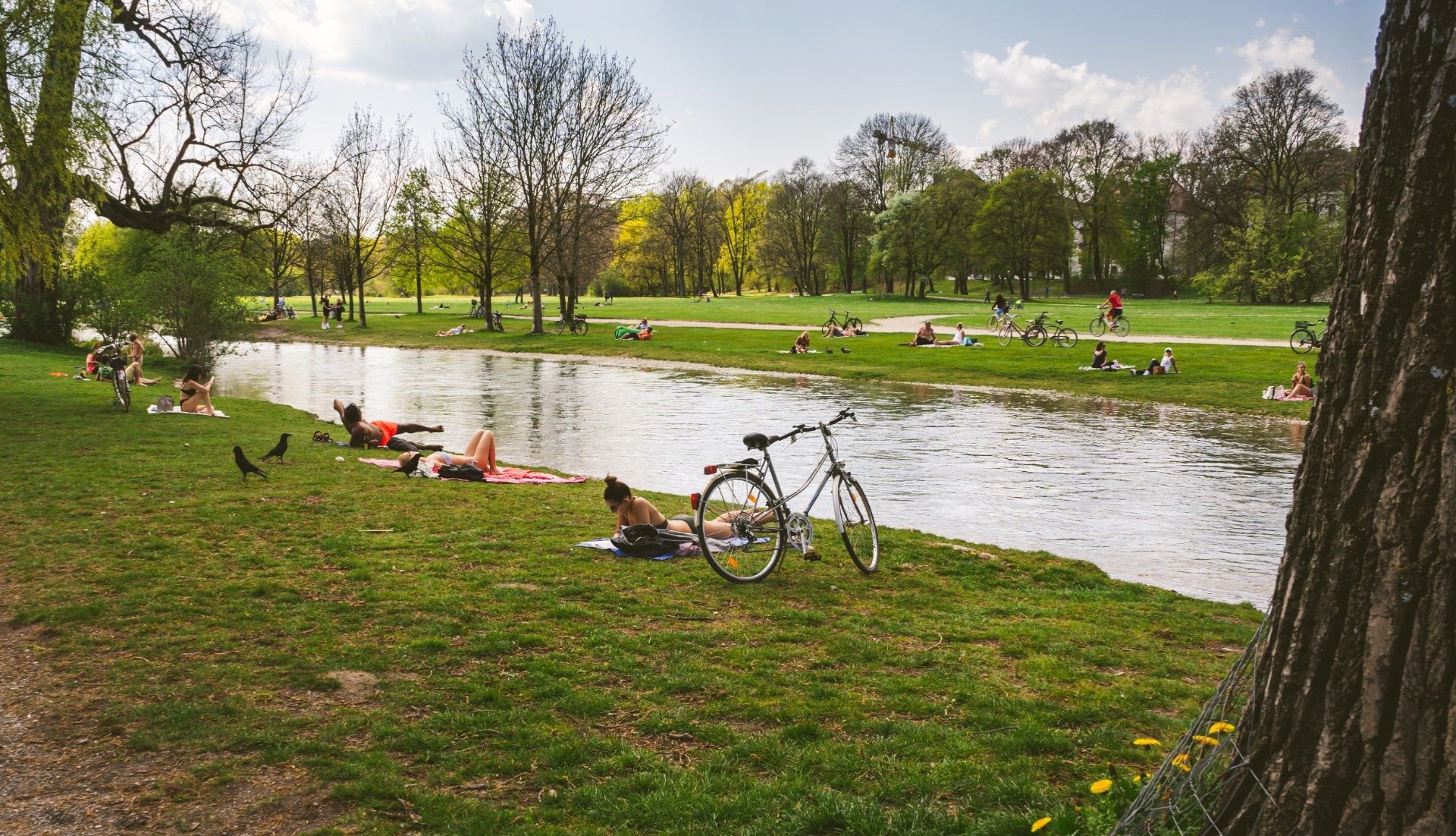 人们在慕尼黑英国花园的水边草地上休憩